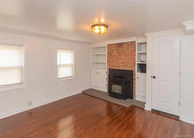 an empty room with wooden floor fireplace and windows