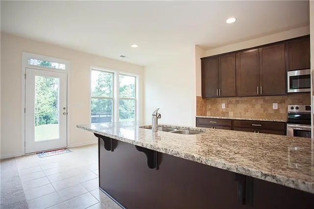 a kitchen with stainless steel appliances granite countertop a stove a sink and a microwave