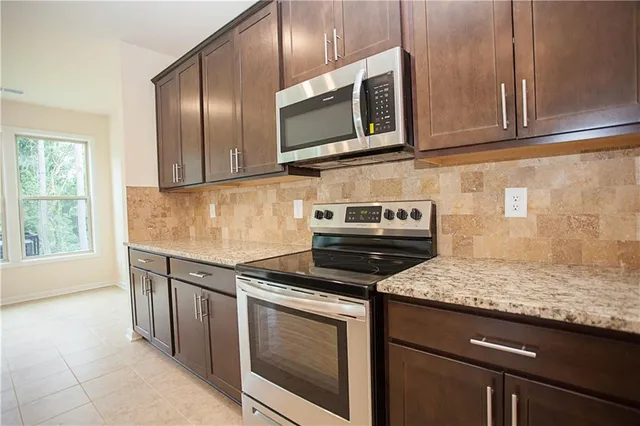 a kitchen with stainless steel appliances kitchen island granite countertop a refrigerator a sink dishwasher a stove with white cabinets and wooden floor