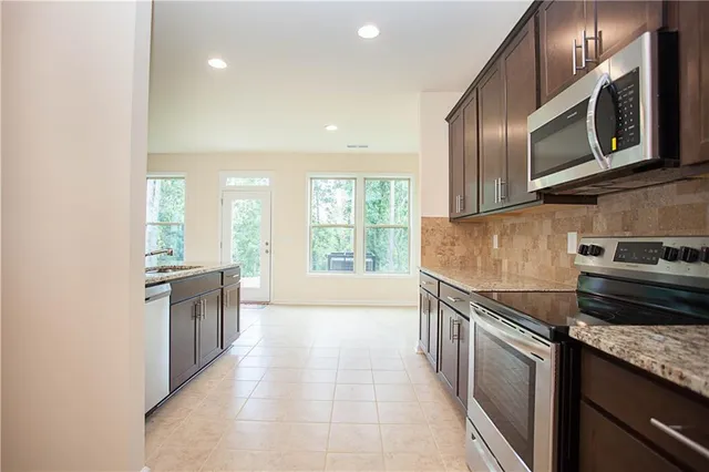 a kitchen with stainless steel appliances granite countertop a sink a stove and microwave