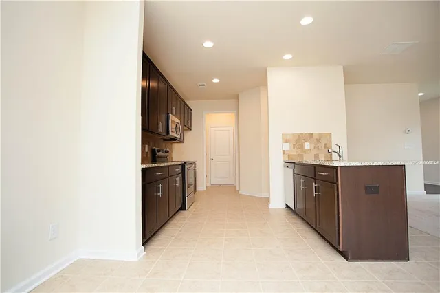 a large kitchen with kitchen island granite countertop a refrigerator oven a sink and dishwasher