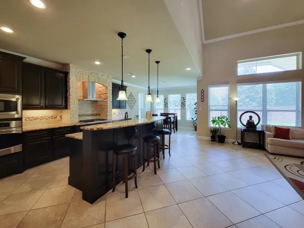 a kitchen with a sink a counter top space appliances and a living room view