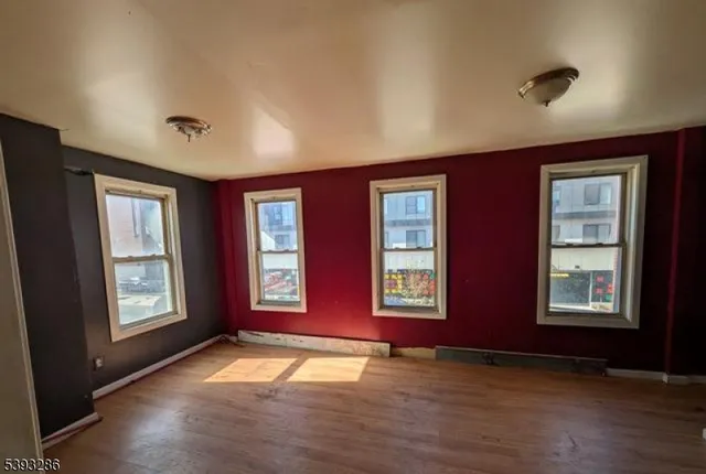 a view of an empty room with window and wooden floor