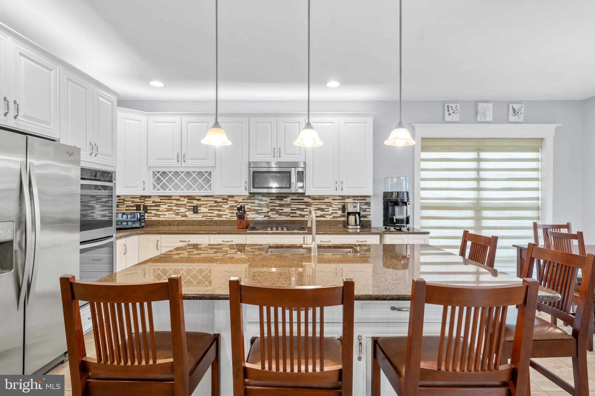 507 Jones Lane Rehoboth Beach, DE 19971 - Photo 11 of 62 a kitchen with a table chairs wooden cabinets and stainless steel appliances