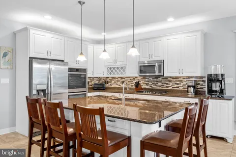 a kitchen with a table chairs wooden cabinets and stainless steel appliances