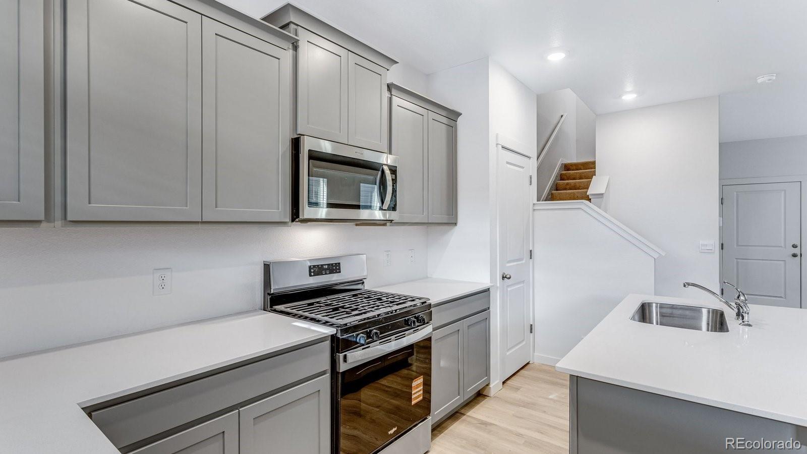 1358 South Chester Street, Unit B Denver, CO 80247 - Photo 22 of 42 a kitchen with granite countertop a sink a stove top oven and cabinetry