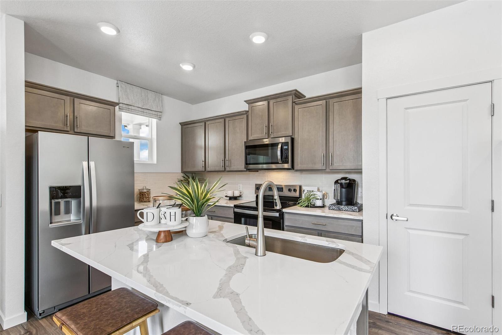 1358 South Chester Street, Unit B Denver, CO 80247 - Photo 6 of 42 a kitchen with white cabinets and stainless steel appliances