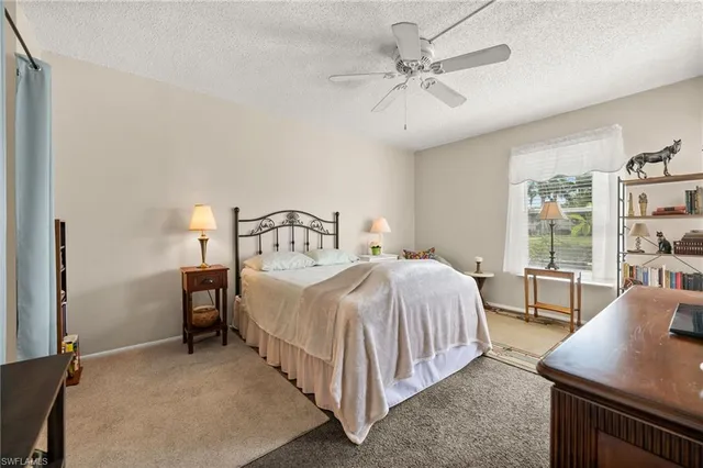 a bedroom with a bed a large window with table and chair
