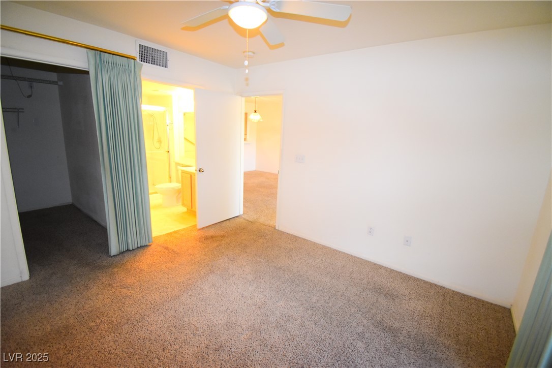 1901 Villa Palms Court, Unit 101 Las Vegas, NV 89128 - Photo 11 of 19 Unfurnished bedroom featuring carpet floors, ensuite bathroom, a ceiling fan, and a spacious closet