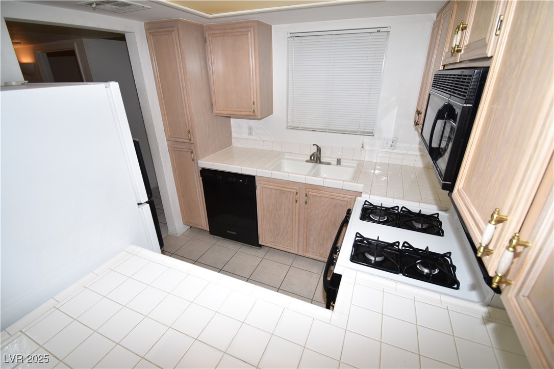 1901 Villa Palms Court, Unit 101 Las Vegas, NV 89128 - Photo 6 of 19 Kitchen featuring light brown cabinetry, black appliances, tile countertops, and light tile patterned floors