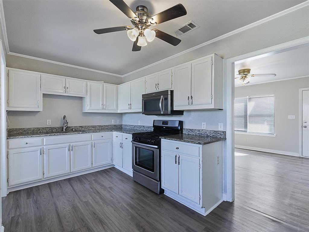 707 Doris Lane Gunter, TX 75058 - Photo 9 of 25 a kitchen with granite countertop stainless steel appliances sink cabinets and wooden floor