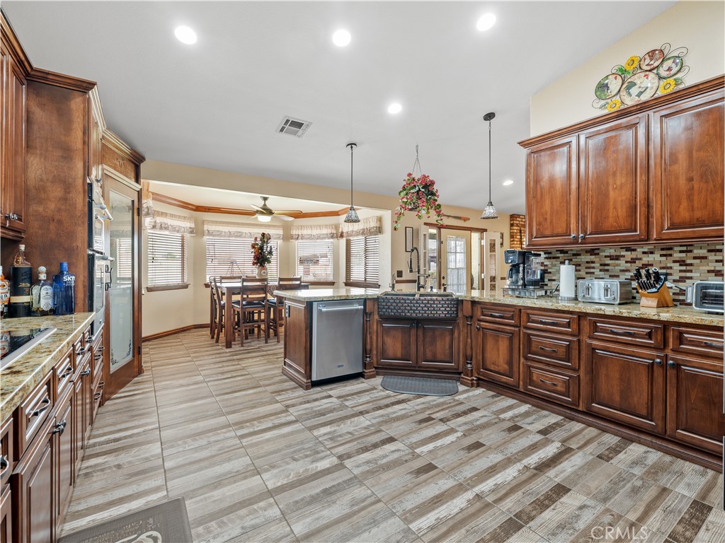 13991 Jicarilla Road Apple Valley, CA 92307 - Photo 12 of 44 a kitchen with stainless steel appliances kitchen island granite countertop a large stove a sink dishwasher and cabinets with wooden floor