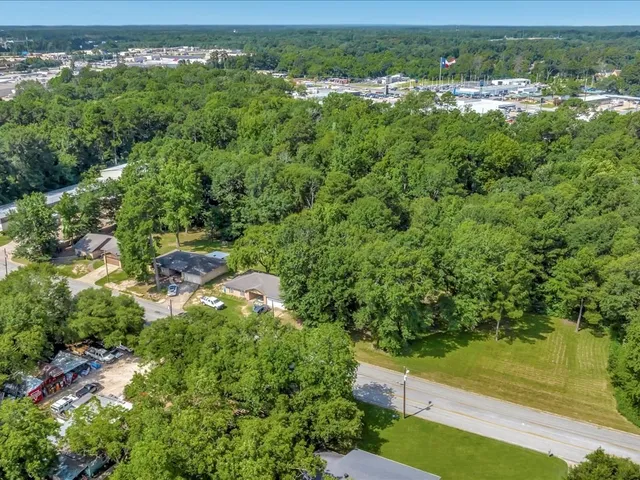 an aerial view of residential houses with outdoor space and trees