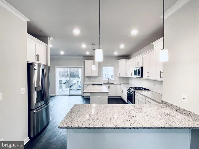 a large kitchen with kitchen island a large counter top stainless steel appliances and cabinets