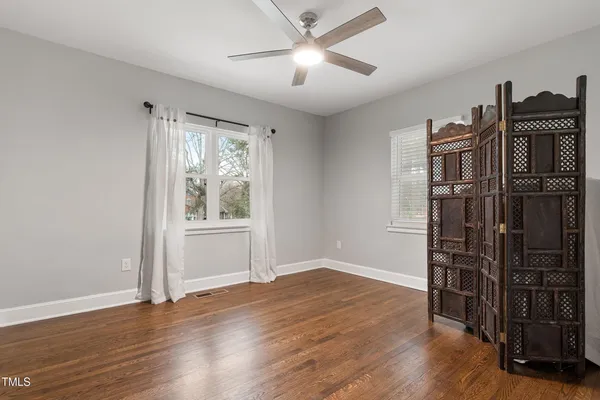 a view of empty room with wooden floor and fan