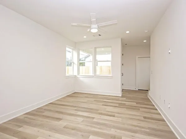 an empty room with wooden floor and windows