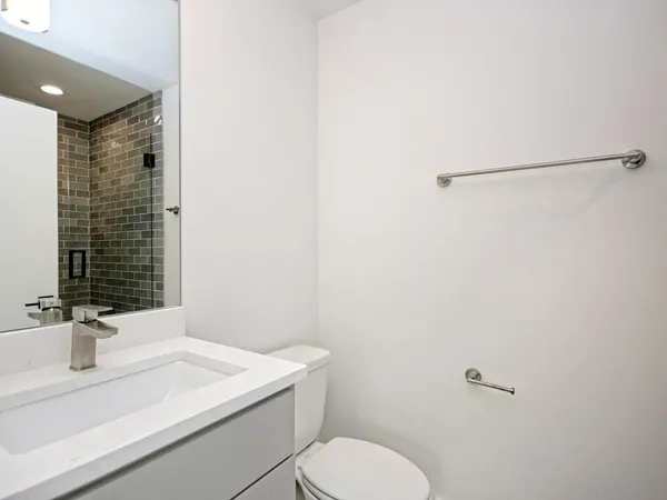 a bathroom with a granite countertop sink toilet and mirror
