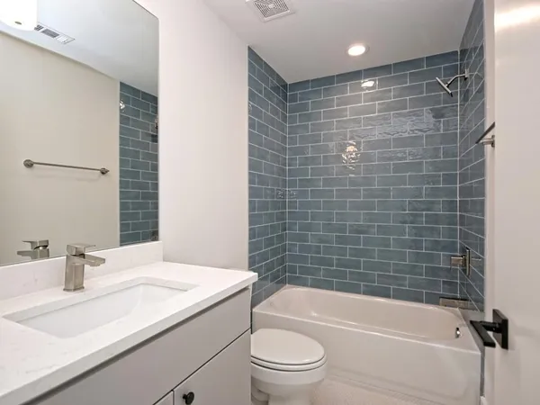 a bathroom with a granite countertop bathtub shower sink vanity and toilet