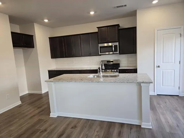 a kitchen with granite countertop a sink a stove and refrigerator