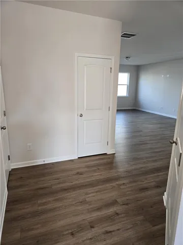 a view of an empty room with wooden floor and window