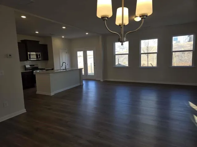 an open kitchen with wooden floor and stainless steel appliances