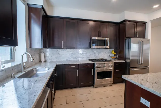 a kitchen with granite countertop a stove sink and refrigerator
