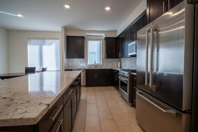 a kitchen with stainless steel appliances granite countertop a refrigerator a sink and a stove