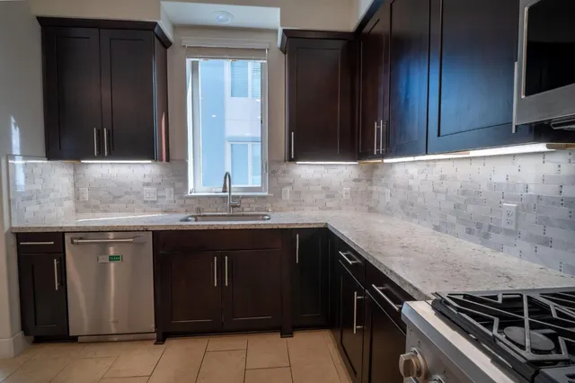 a kitchen with granite countertop a sink cabinets and stainless steel appliances