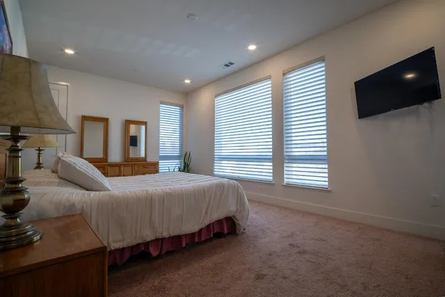 a spacious bedroom with a bed and a flat screen tv