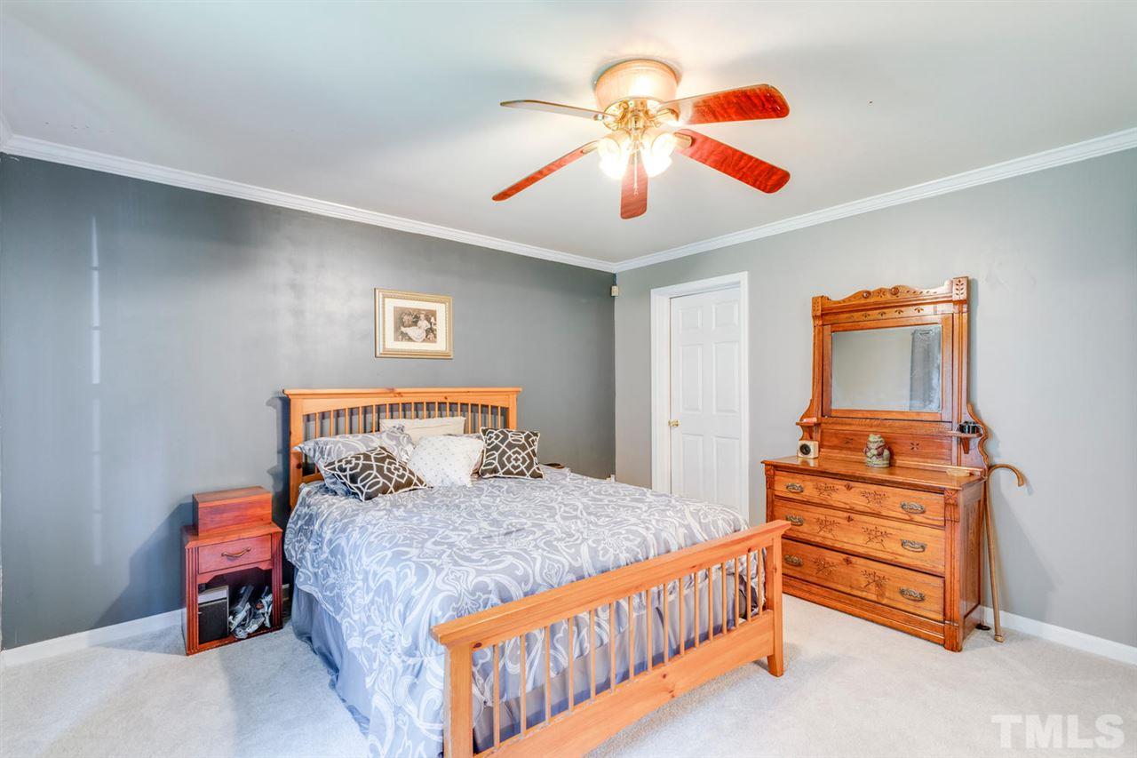 190 Landmark Road Willow Spring, NC 27592 - Photo 12 of 25 a bedroom with a bed and a chandelier