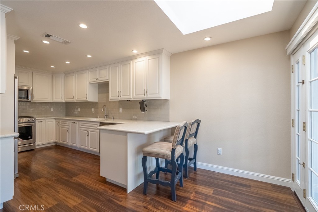 5965 Maybrook Circle Riverside, CA 92506 - Photo 9 of 25 a large white kitchen with wooden floor and stainless steel appliances