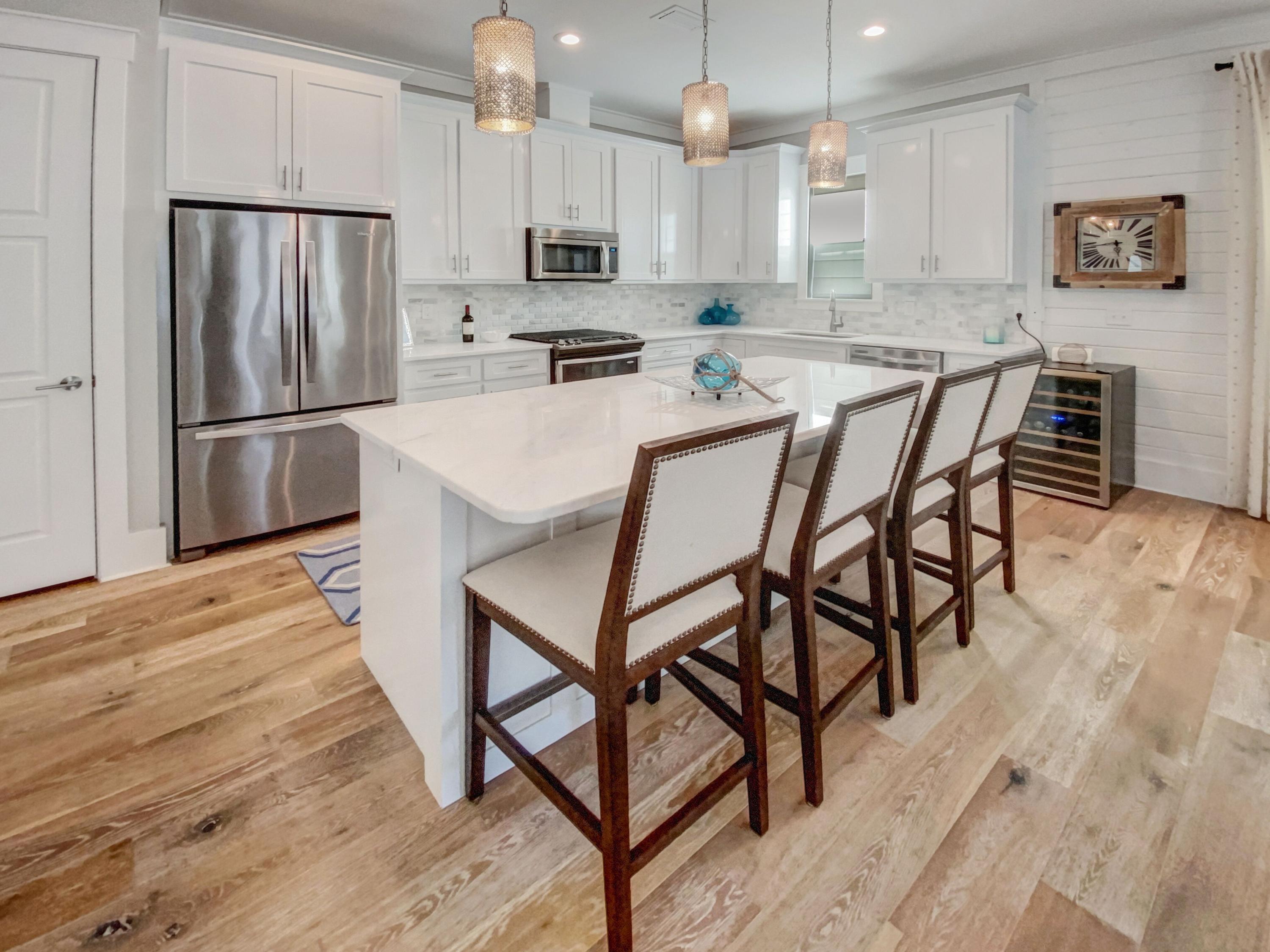 158 East Blue Crab Loop Inlet Beach, FL 32461 - Photo 5 of 43 a kitchen with stainless steel appliances a refrigerator a stove a sink a dining table and chairs
