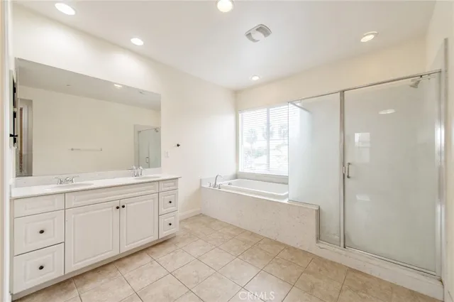 a spacious bathroom with a double vanity sink a mirror and a shower