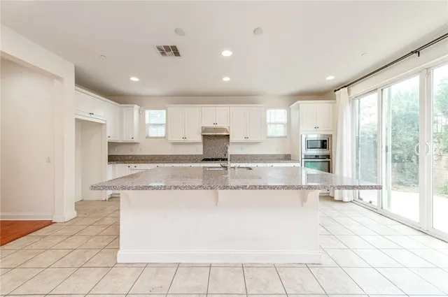 a large kitchen with granite countertop a large counter top and stainless steel appliances