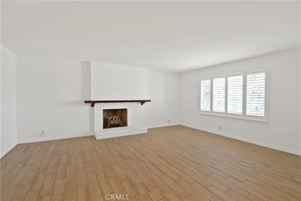 an empty room with windows and fireplace