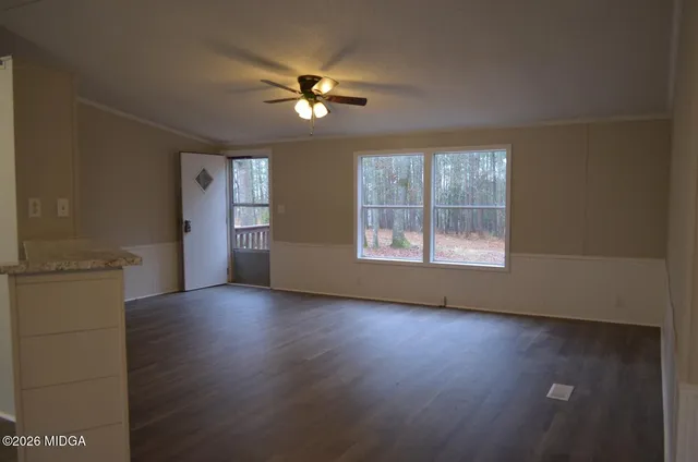 an empty room with wooden floor chandelier fan and windows