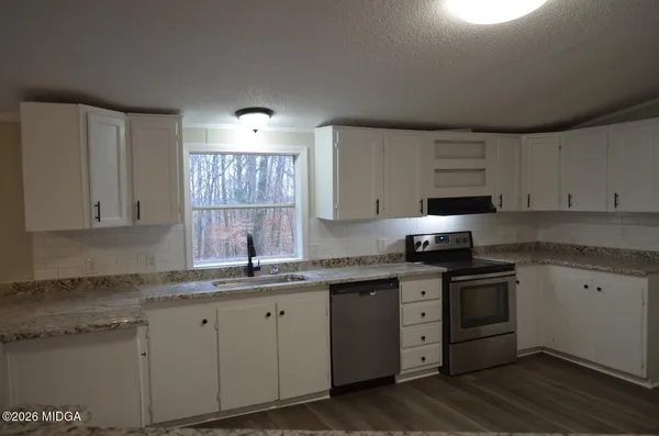 a kitchen with cabinets appliances a sink and a window