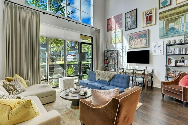a living room with furniture a flat screen tv and a floor to ceiling window