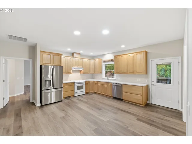 a kitchen with stainless steel appliances wooden floors and wooden cabinets