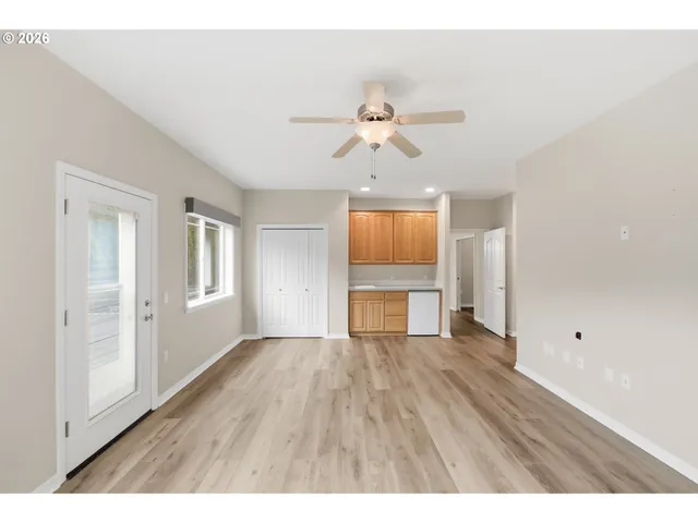 a view of empty room with wooden floor and fan