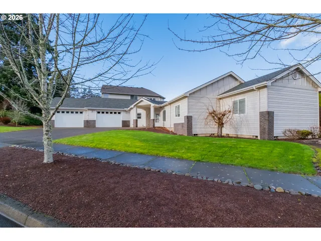 a view of a house with a yard and large tree