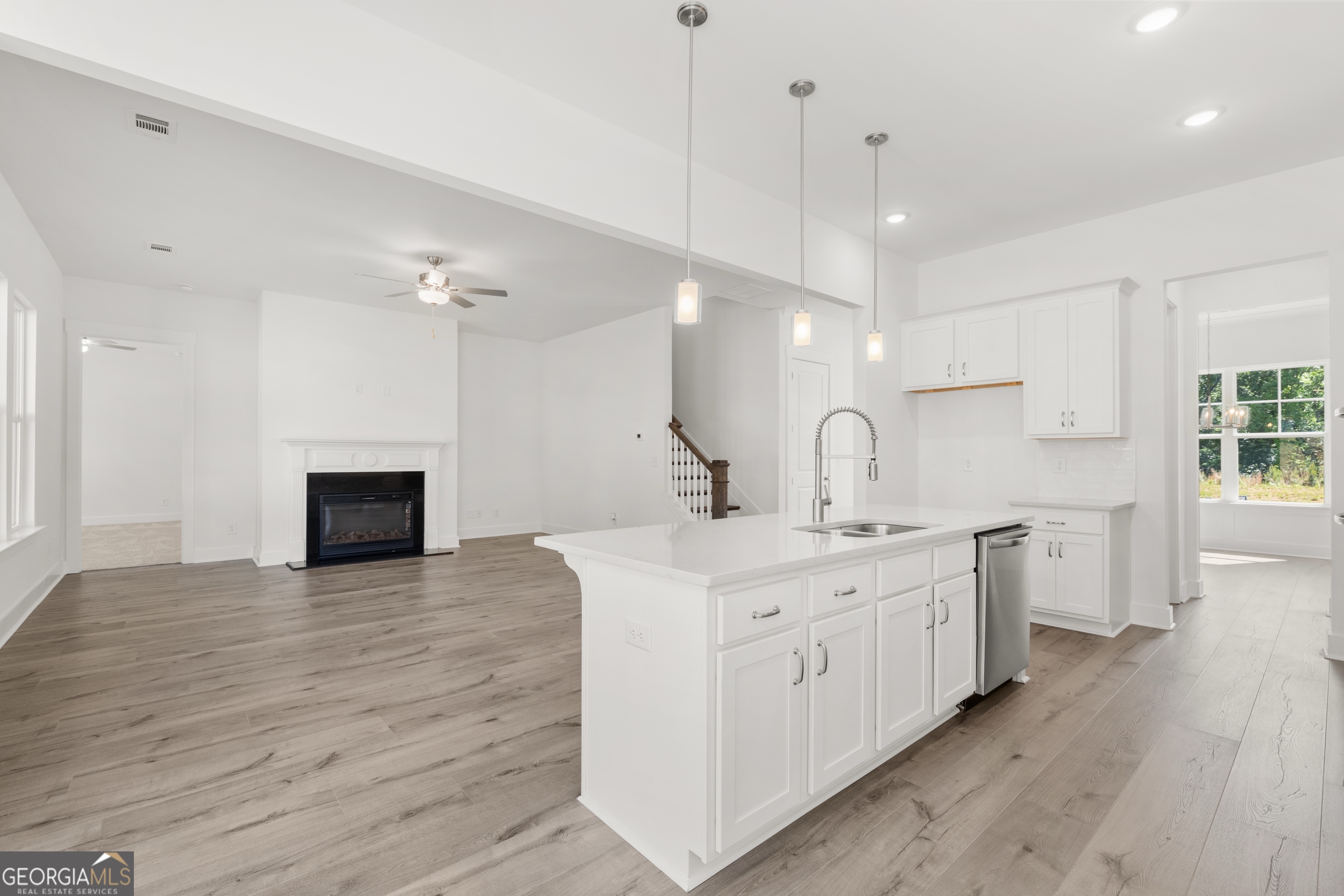 15 Overview Court Hoschton, GA 30548 - Photo 16 of 43 a large white kitchen with a sink a fireplace and wooden floor