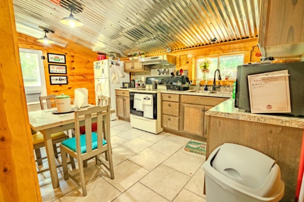 2167 Powdermill Hill Road Lawrenceburg, TN 38464 - Photo 9 of 33 a kitchen with a sink a stove and white cabinets with wooden walls