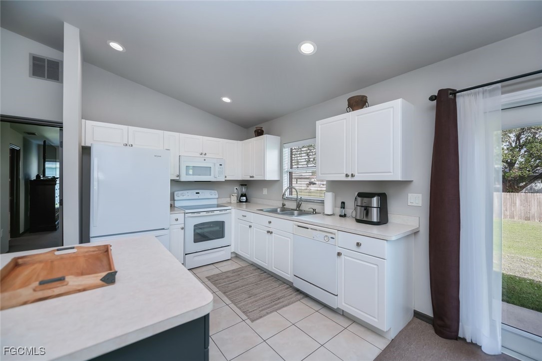 4108 13th Street Southwest Lehigh Acres, FL 33976 - Photo 4 of 48 a kitchen with white cabinets a sink stove and refrigerator