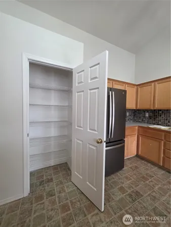 a kitchen with granite countertop a refrigerator and white cabinets