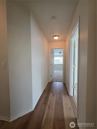 a view of a hallway with wooden floor and closet