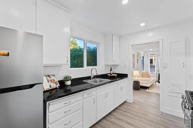 a kitchen with granite countertop a sink and white cabinets