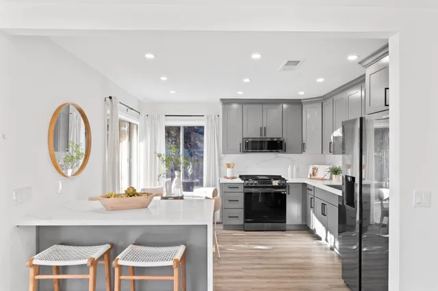 a kitchen with stainless steel appliances granite countertop a stove top oven a sink and a refrigerator