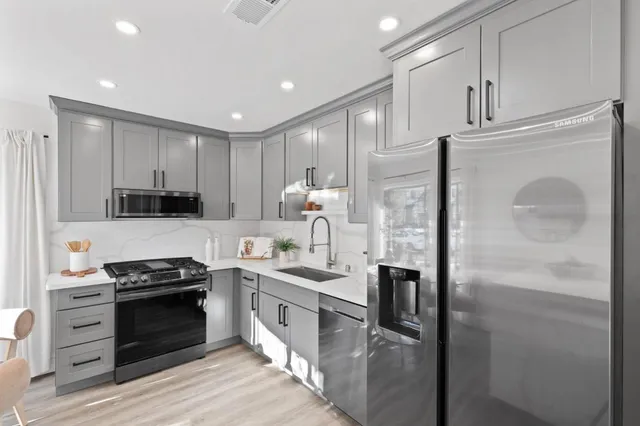 a kitchen with stainless steel appliances granite countertop a refrigerator a stove and a sink with wooden floor