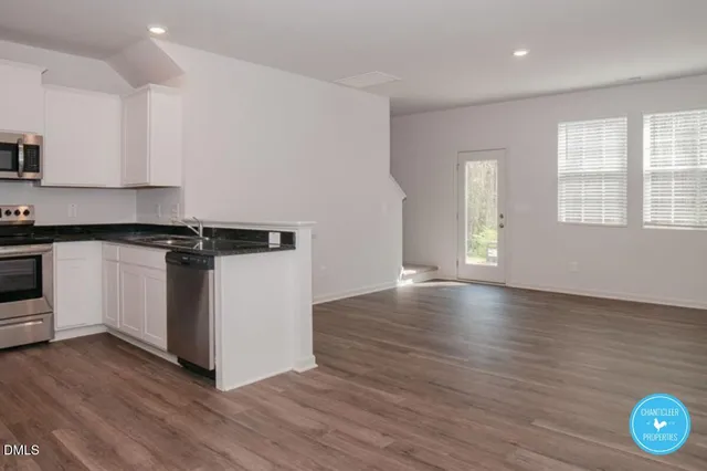 a view of a kitchen with wooden floor and a window